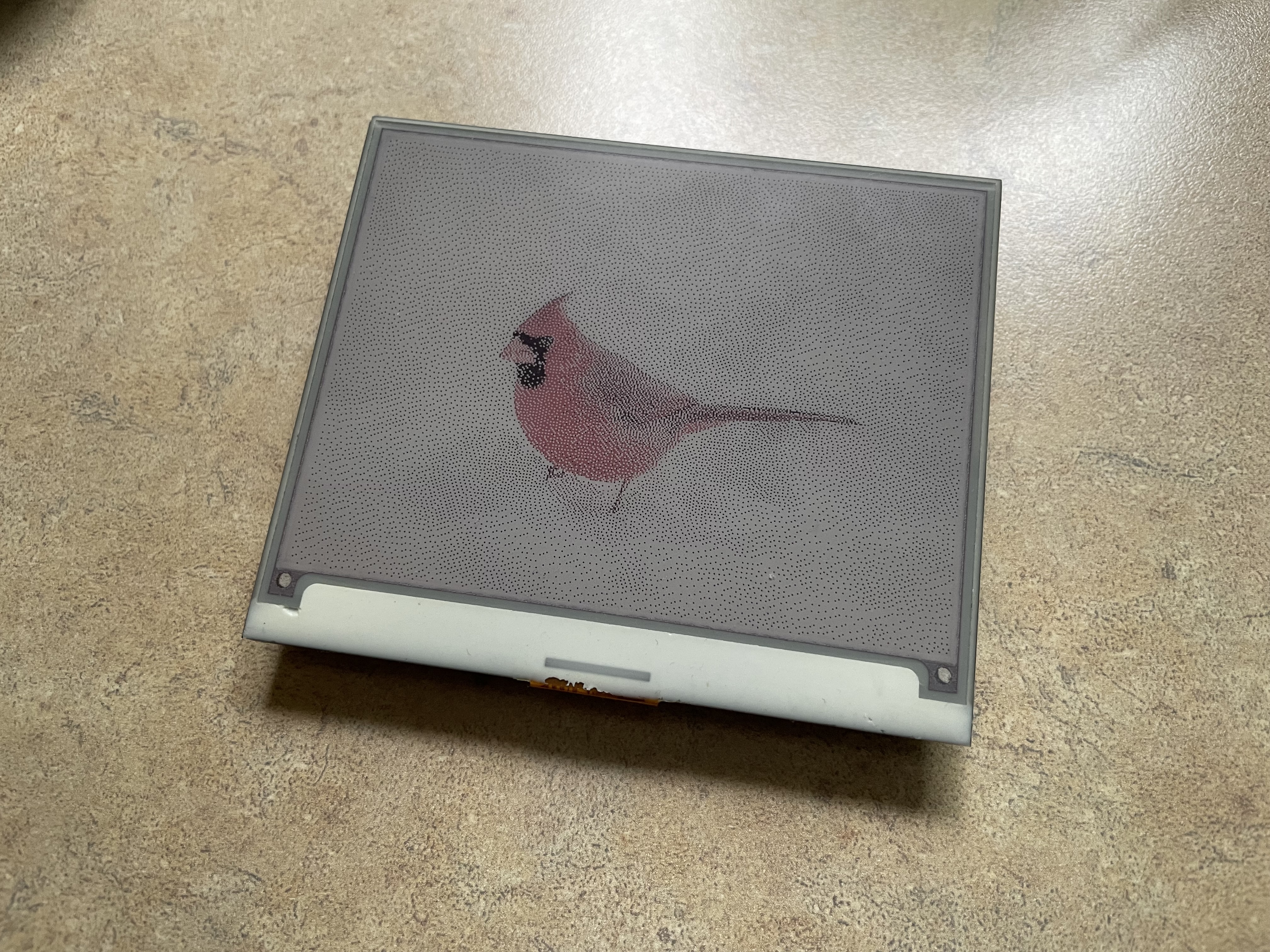 An eInk display showing an image of a cardinal.