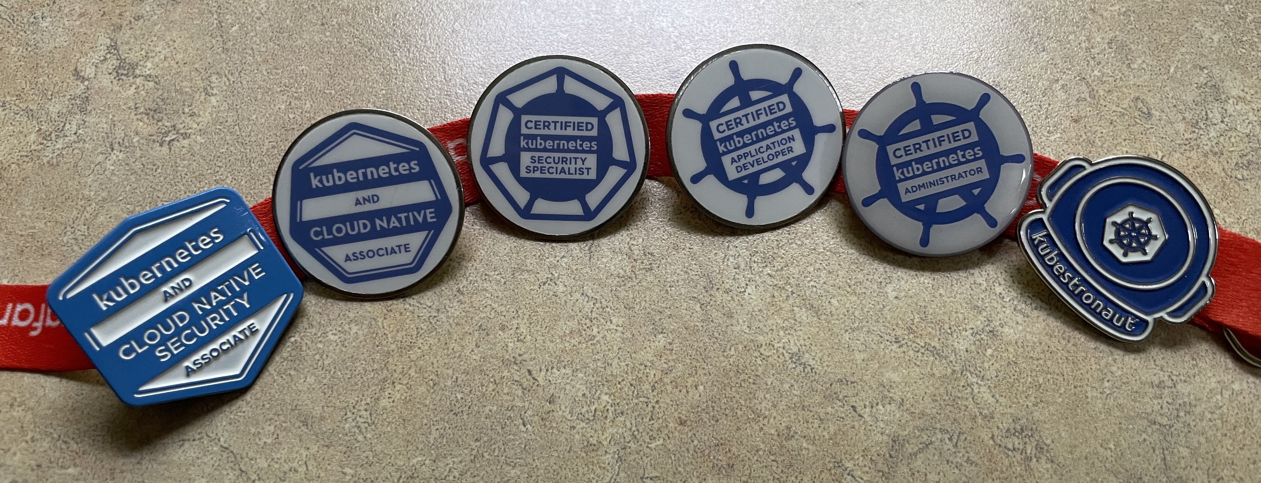 A lanyard with metal pins for different CNCF certifications and a Kubestronaut pin.