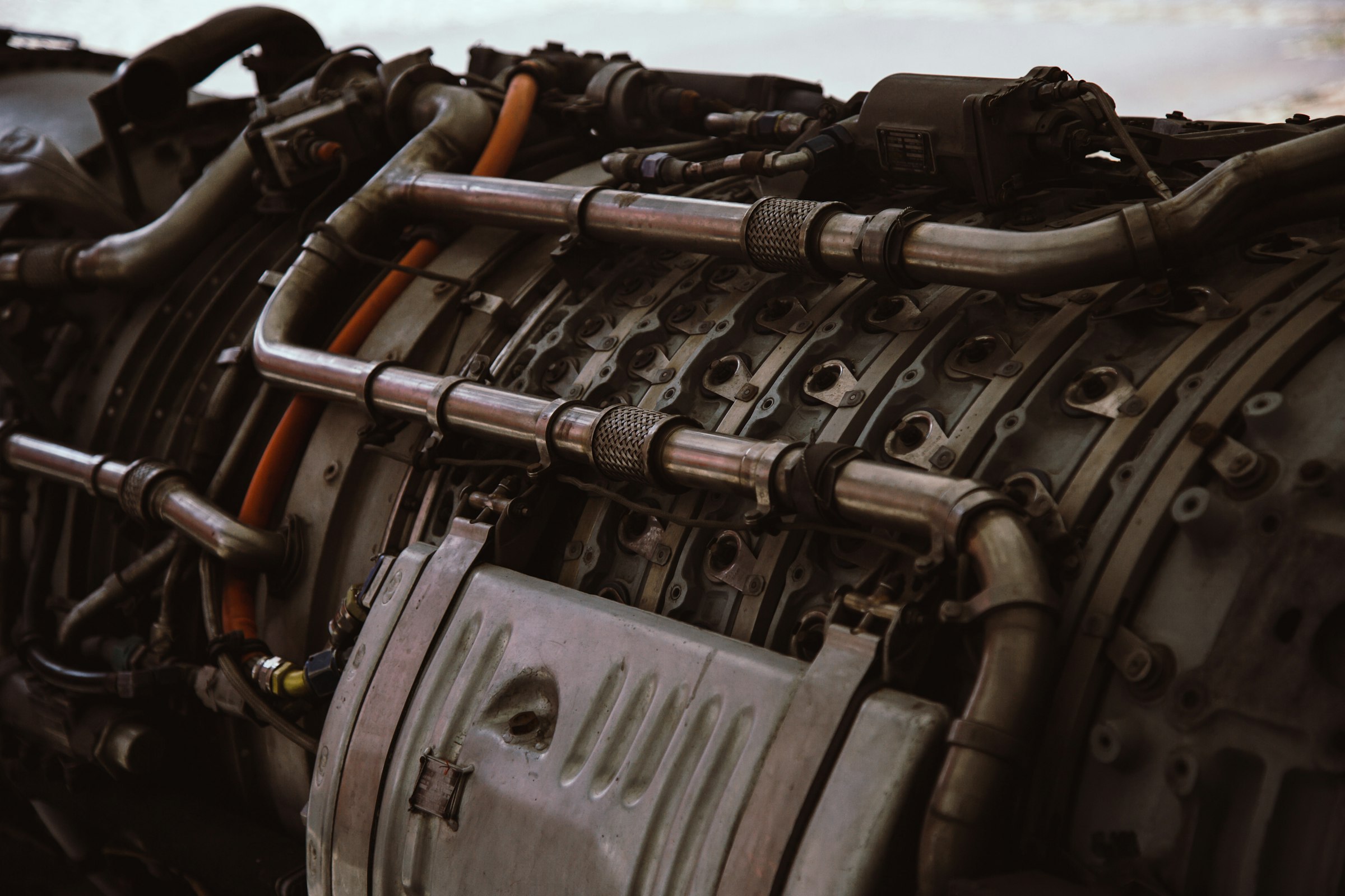 A close-up of an aircraft turbine engine, densely wrapped in metal piping and fittings.